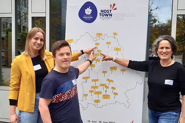 Deborah Specht, Pascal und eine weitere Person zeigen auf die Landkarte von Special Olympics